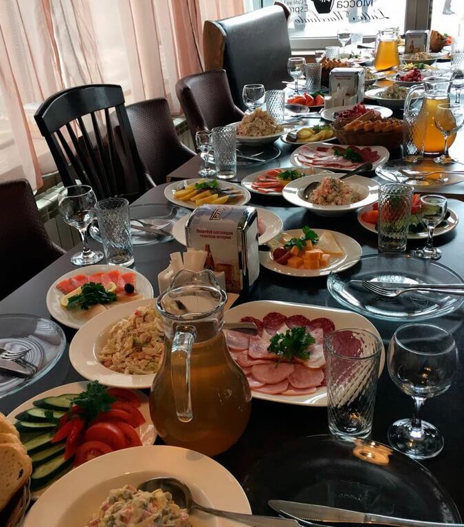 Накрытый поминальный стол в кафе: закуски, салаты и компот